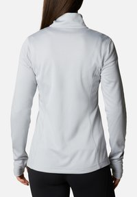 Hellegrauer Langarm-Pullover mit hohem Kragen, strukturiertem Stoff und figurschmeichelndem Design. Verfügt über einen abgerundeten Saum und Daumenlöcher an den Ärmeln.