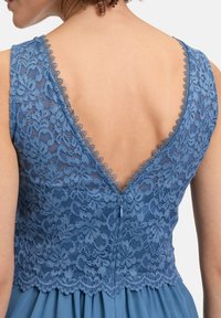 Blauwe kantjurk met een diepe V-hoofd, bloemig kantpatroon, gegolfde randen en een verborgen rits in de taille voor sluiting.