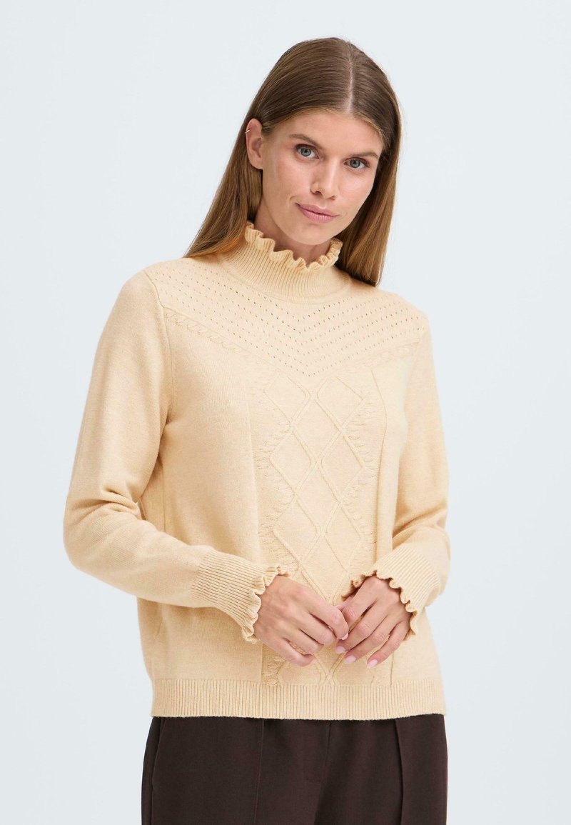 Pull en maille beige avec un col haut froncé, des motifs en losanges sur le devant et des poignets de manches froncés. Texture douce et coupe décontractée.