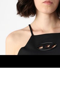 Black halter-top with a glossy black oval logo detail, featuring thin straps and a smooth texture, highlighting a minimalist design.