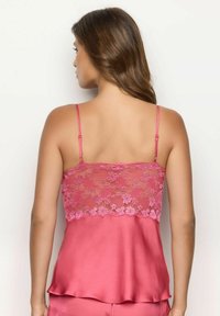 Roze satijnen camisole met kanten rugdetail, dunne verstelbare schouderbandjes en een ontspannen pasvorm, met een gladde textuur en een lichte flare.