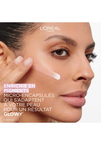 Produit de soin de la peau L'Oreal présenté sous la forme d'une lotion crémeuse, blanc cassé, appliquée sur la peau ; texture lisse avec un éclat subtil, mettant en valeur l'éclat naturel.