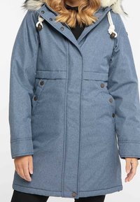 Parka blu, lunghezza ginocchio, realizzata in tessuto testurizzato, con cappuccio foderato in pelliccia e bottoni a pressione su tasche e parte anteriore. Presenta un cappuccio regolabile con cordino.