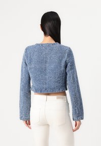Geknipt blauw sweater van gestructureerde stof met lange mouwen, met een ronde hals en een ruwe zoom, gecombineerd met witte jeans.