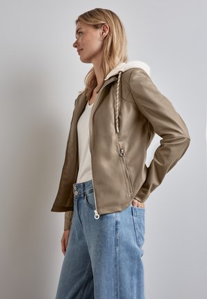 Ljust brunt faux läderjacka med vit huva, dragkedja fram och fickor. Kombineras med ljusblå vida jeans.