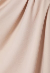 Vaalea persikkakankaan kangas, jossa on sileä pinta, hienovaraiset poimutukset ja hienoa kudontakuviota. Sopii vaatteisiin tai verhoiluun.