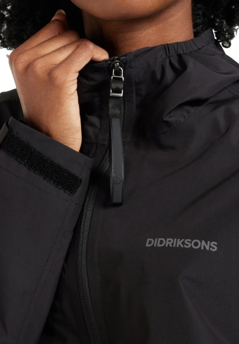Schwarze wasserdichte Jacke mit verstellbarem Kragen, Reißverschluss und Klettverschluss-Details; verfügt über eine dezente Markenkennzeichnung "DIDRIKSONS" auf dem Stoff.