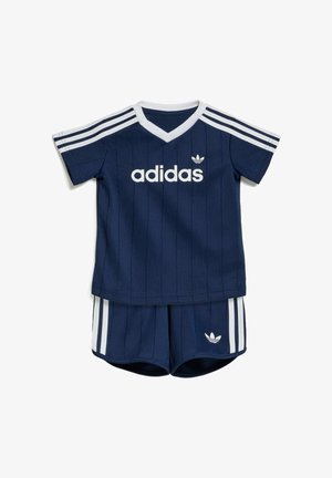 Tenue bébé Adidas bleu marine avec des bandes blanches sur les épaules et les shorts, avec le logo Adidas sur le t-shirt et les shorts.