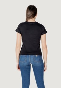 Zwarte katoenen T-shirt met korte mouwen, aansluitende pasvorm en een ronde halslijn, gecombineerd met blauwe spijkerbroek met achterzakken.