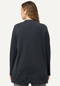 Mörkgrå tröja med långa ärmar och rund halsringning. Har en avslappnad passform och ribbad struktur vid ärmsluten och nederkanten.