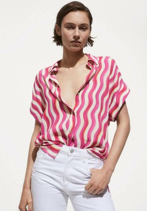 Short-sleeve shirt featuring a pink, white, and orange wave pattern, made of lightweight fabric, paired with white high-waisted jeans.