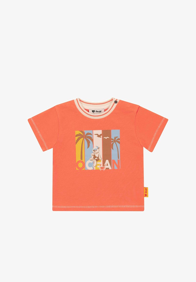 T-shirt corail à manches courtes avec un col rond, présentant un visuel coloré d'un ours et des palmiers. Tissu en coton doux avec des coutures contrastantes.