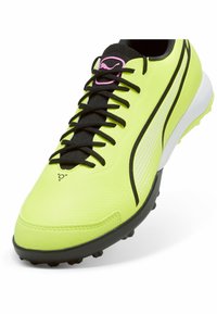 Scarpa da calcio gialla neon con lacci neri e tomaia testurizzata, caratterizzata da un design a strisce bianche e nere. Suola in gomma nera stampata.