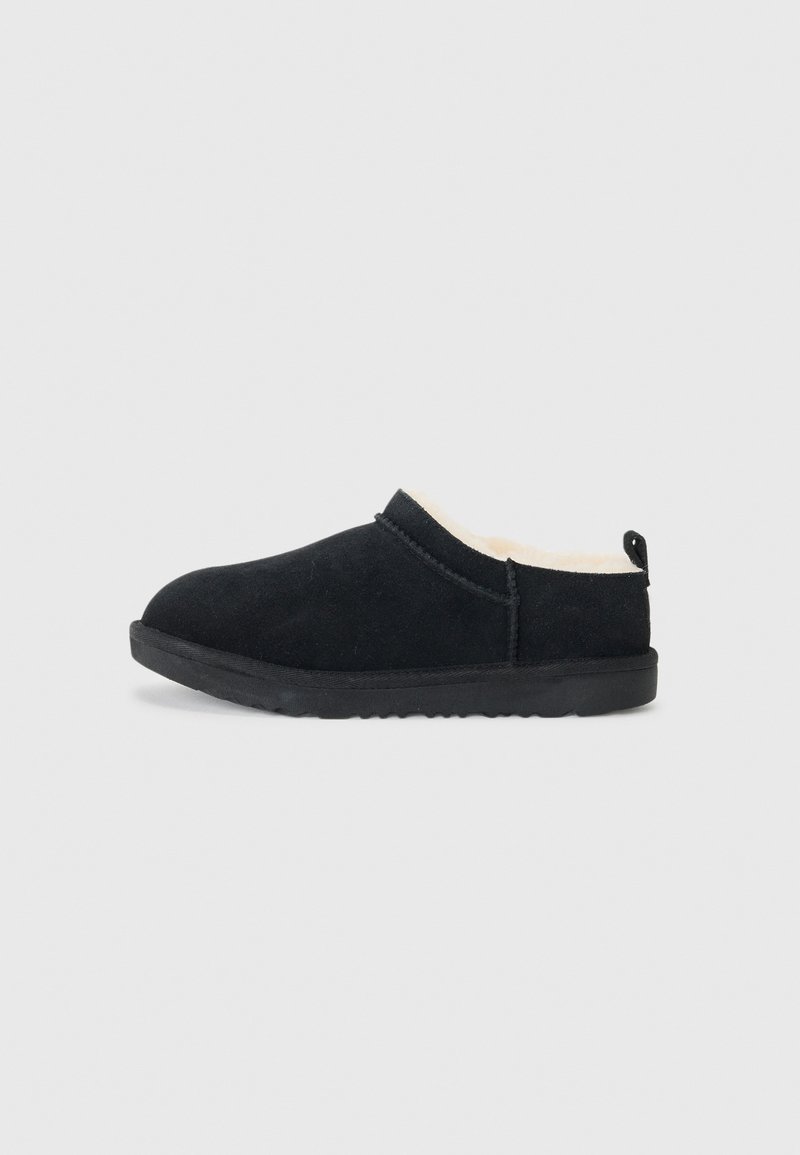 Svart mocka slip-on sko med en mjuk krämfärgad innerfoder, platt gummisula, rund tå och en dragflik bak. Enkel, minimalistisk design.