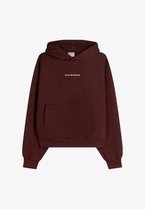 Burgundy hoodie med en framficka, med en guldig "OVRNRM"-logga. Tillverkad av mjuk bomull, har den en avslappnad passform och ribbade ärmslut.