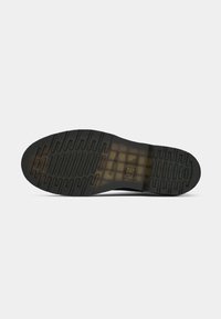 Semelle de chaussure avec motif antidérapant texturé et section intermédiaire translucide affichant le logo et les informations de taille sur un fond uni.
