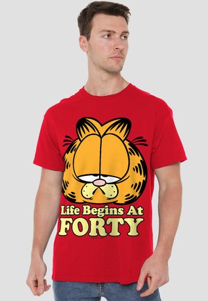 Rotes Baumwoll-T-Shirt mit großem Grafikdruck eines Cartoon-Katzenkopfes und dem Text "Das Leben beginnt mit FÜNFZIG" in Gelb und Schwarz.