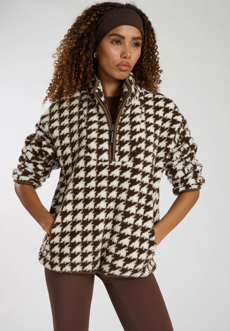 Pullover in pile con motivo houndstooth marrone e crema, dotato di zip a mezza lunghezza, colletto alto e tasche laterali; tessuto morbido e testurizzato.