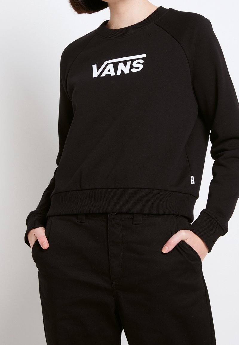 Felpa nera con colletto a girocollo, maniche raglan e logo Vans bianco sul petto. Presenta un orlo e polsini a coste.
