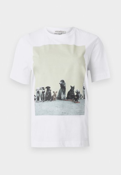 T-shirt blanc avec une impression photo sur le devant montrant neuf différentes races de chiens assises en rang sur un sol en béton.