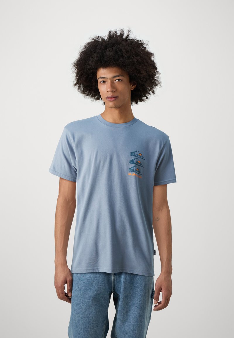 Lichtblauw katoenen t-shirt met een grafisch ontwerp op de borst van bergen en golven in oranje en blauw, korte mouwen en een relaxte fit.