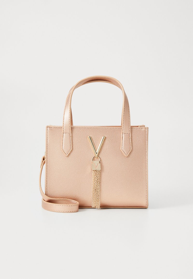 Roza umetna usnjena torba z teksturirano površino, ročaji na vrhu, zlato-tonirana kovinska oprema in dekorativni pompon. Vključena je nastavljiva naramnica.