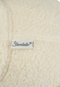 Cream-colored, textured fabric showing looped fibers, with a visible white label featuring "Sterntaler" in grey lettering.