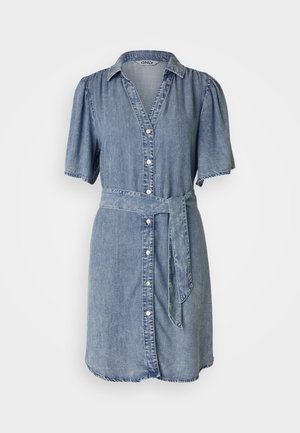 Φόρεμα πουκαμίσα από τζην με κοντά φουσκωτά μανίκια, κουμπιά μπροστά, ζώνη στη μέση και σκιές στις άκρες. Το χρώμα είναι ανοιχτό μπλε με λεία υφή.