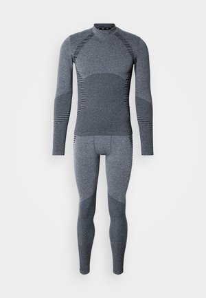 Sous-vêtement thermique gris à manches longues avec une coupe ajustée, des panneaux texturés et des accents côtelés. Tissu lisse, construction sans coutures sur toute la surface.