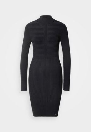 Abito in maglia nera a coste con colletto alto, maniche lunghe e motivo a strisce verticali. Silhouette aderente che arriva fino a metà coscia.