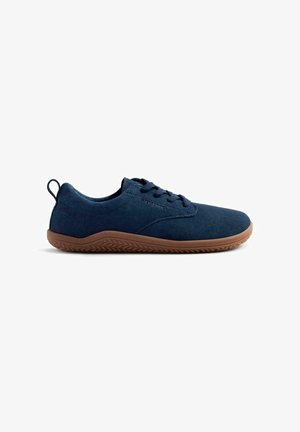 Zapato de ante azul marino con diseño de cordones, perfil bajo y suela de goma con un dibujo texturizado para mayor agarre. Pequeña tira en el talón.