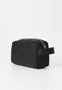 Borsa da toeletta rettangolare nera in tessuto, dotata di cerniera superiore, manico laterale e una superficie liscia. Design minimalista senza motivi.
