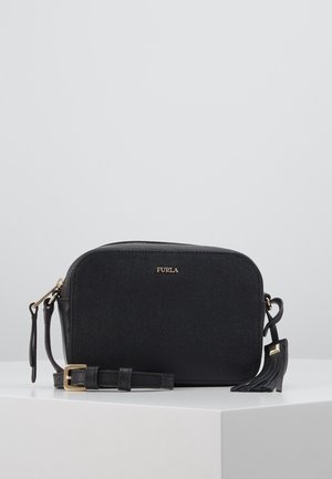 Czarna torebka Furla typu crossbody z regulowanym paskiem, złotą klamrą i ozdobą z frędzli na białym tle na szarym tle.
