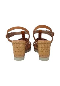 Sandali con tacco alto in pelle marrone con dettagli in paglia intrecciata, cinturini regolabili alla caviglia e tacchi texture, dotati di una suola chiara.