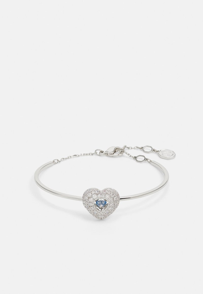 Bracciale d'argento con un fermaglio a forma di cuore, che presenta una pietra blu centrale, circondata da piccoli cristalli trasparenti, e una catena per la regolazione.