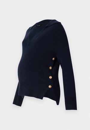 Tume sinine rasedusee särgiga, millel on V-kaelus, ribakujuline tekstuur ja kuldne nööbiga kaunistus külgedel, millel on lõtv ja üle mõõtme sobiv kord.