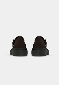 Chaussures en cuir marron avec un bout rond, une surface texturée et une épaisse semelle en caoutchouc noir. Présente un design décontracté avec une accentuation minimale.