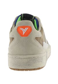 Zapatilla beige con una suela de goma texturizada, parte superior de ante, forro interior verde y azul, y un acento naranja del logo en el talón.