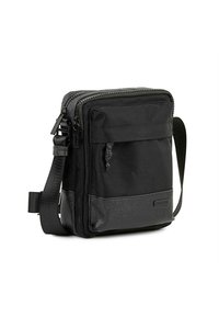 Bolso cruzado negro hecho de tela duradera, con un compartimento principal con cremallera, bolsillo frontal y panel inferior texturizado. Correa ajustable.