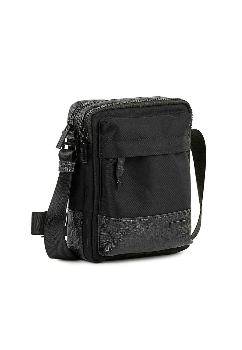 Bolso cruzado negro hecho de tela duradera, con un compartimento principal con cremallera, bolsillo frontal y panel inferior texturizado. Correa ajustable.