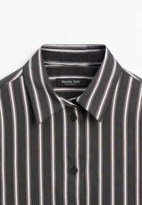 Koszula z kołnierzykiem, zapinana na guziki, w pionowe czarne, białe i brązowe paski, z widocznymi dwoma czarnymi guzikami oraz metką Massimo Dutti wewnątrz.