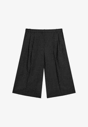 Pantaloni neri a gamba larga con tessuto liscio, pieghe anteriori e vita sartoriale. Il design si estende sotto le ginocchia.