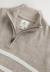 Beige knit sweater with ribbed high collar, half-zip, and two horizontal white stripes across the chest, size medium, brand NEXT.