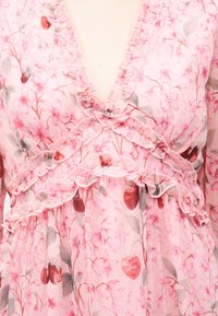 Διάφανο ροζ φόρεμα με floral μοτίβα, διακοσμημένο με βολάν και βαθύ ντεκολτέ σε σχήμα V, με κόκκινα και γκρι σχέδια λουλουδιών και φρούτων.