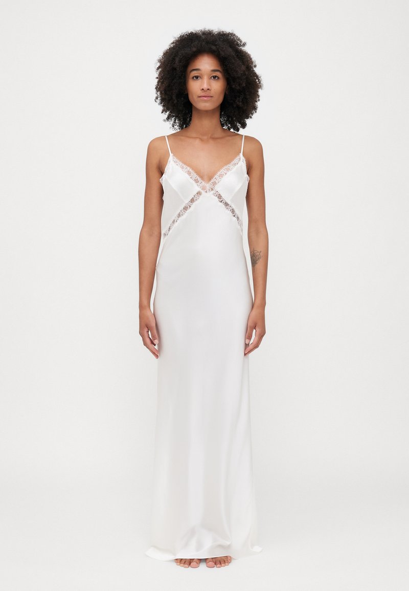 Seiden-Nachtkleid in weiß mit Spitze entlang des Ausschnitts und der Seiten, ausgestattet mit dünnen Spaghettiträgern und einer fließenden, geraden Silhouette.