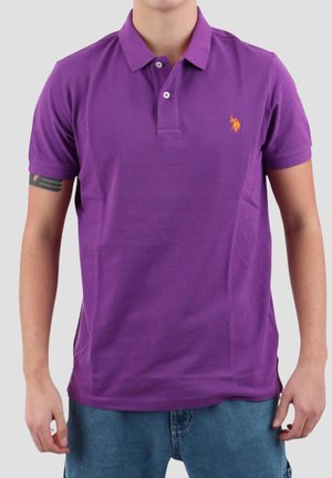 Camisa polo de algodón morada con cuello y mangas cortas, que presenta un pequeño logo naranja en el lado izquierdo del pecho.