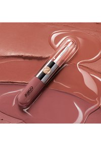 Leppestifttube med rosatoner i nøyale nyanser merket "KIKO MILANO" og "Unlimited Double Touch" på en teksturert, uskarp bakgrunn med matchende leppefarger.