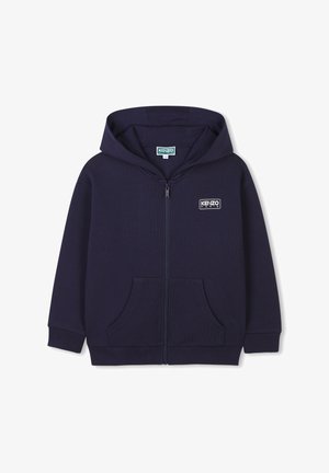 Hoodie zippé bleu marine avec une poche kangourou, des poignets côtelés et un patch logo sur la poitrine gauche ; fabriqué en matériau en coton texturé.