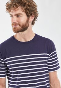 Mørkeblå t-shirt med horisontale hvide striber, crew neckline, korte ærmer og en blød, glat stoftekstur.