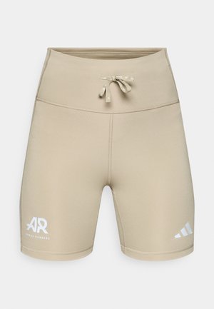 Beige atletiske shorts med tettsittende design, elastisk midjebånd, snøring og hvite logodetaljer. Laget av glatt, elastisk stoff.